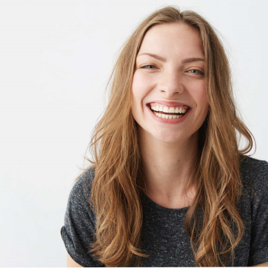 Young woman smiles with absolutely no inhibition: a big, whole-hearted laugh that shows nearly all of her teeth.